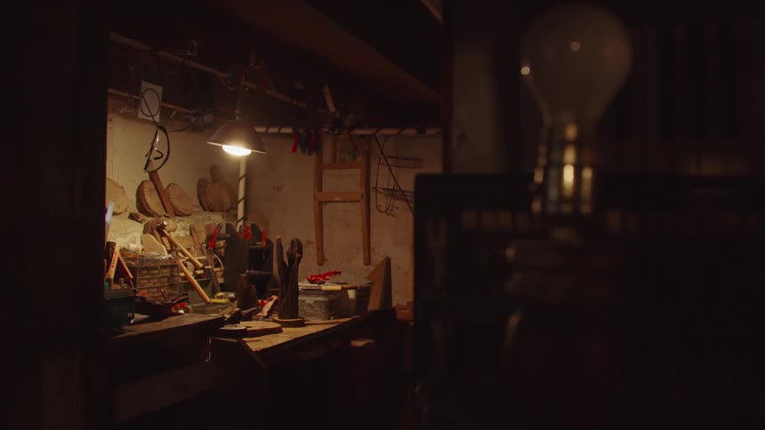 Garage with a light shining on a workbench as an elderly man walks out