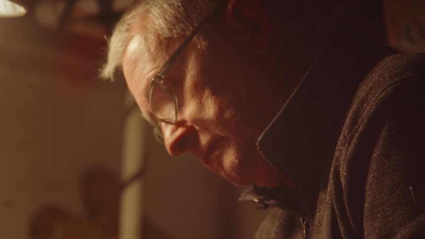 Elderly man wearing glasses working inside his garage