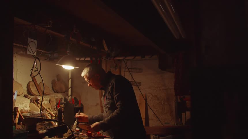 Man works in a carpentry workshop holding a piece of wood