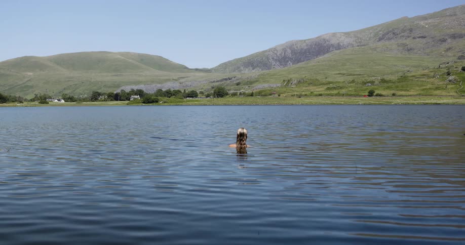 Woman bathing in a lake with mountains in the background