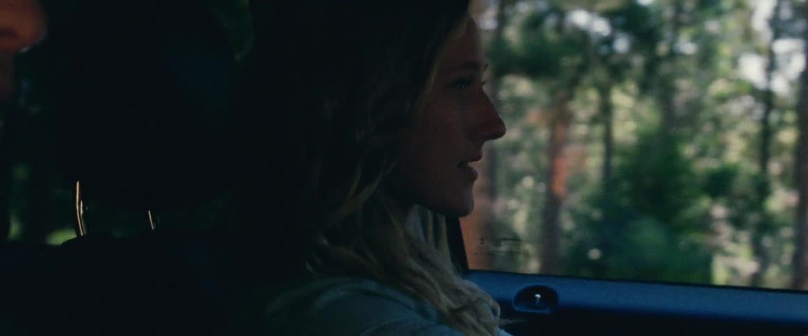 Woman driving vehicle looks over and smiles