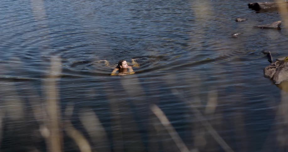 The woman is swimming in the lake water