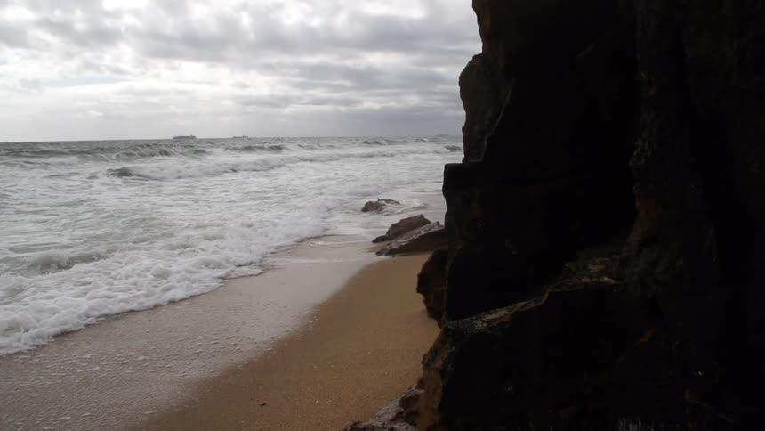 Ocean waters crashing on a beach near rocky cliffs