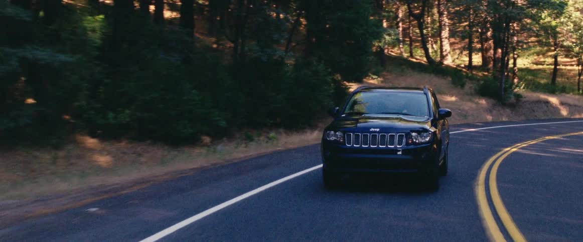 Black jeep driving down a country road