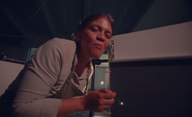 A woman uses a fork to taste food as she straightens herself after bending over