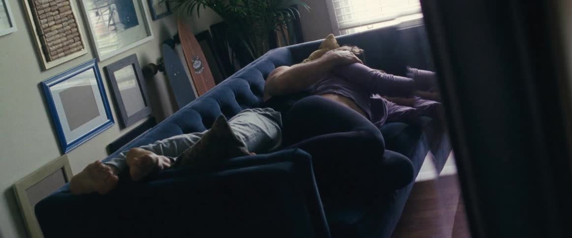 A man and woman lay together on the couch