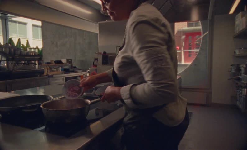 Cook adding chopped ingredients into a pan on the stove
