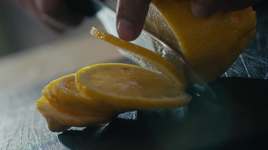 Lemon being sliced into rounds on a cutting board