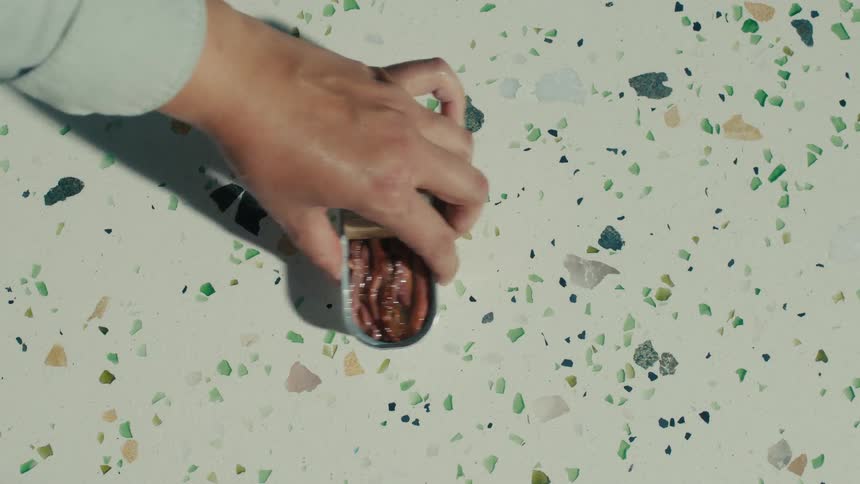 A hand picking an opened can of fish