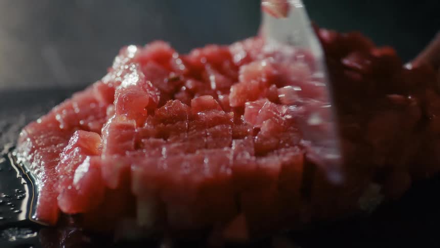 Chef preparing ground beef slices in small chunks on a fryer