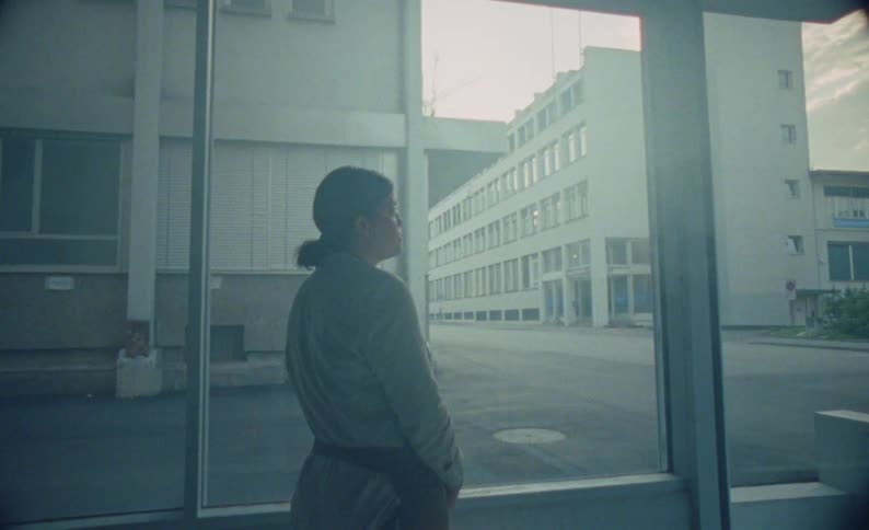 Woman seen from behind looking through the window at the empty street