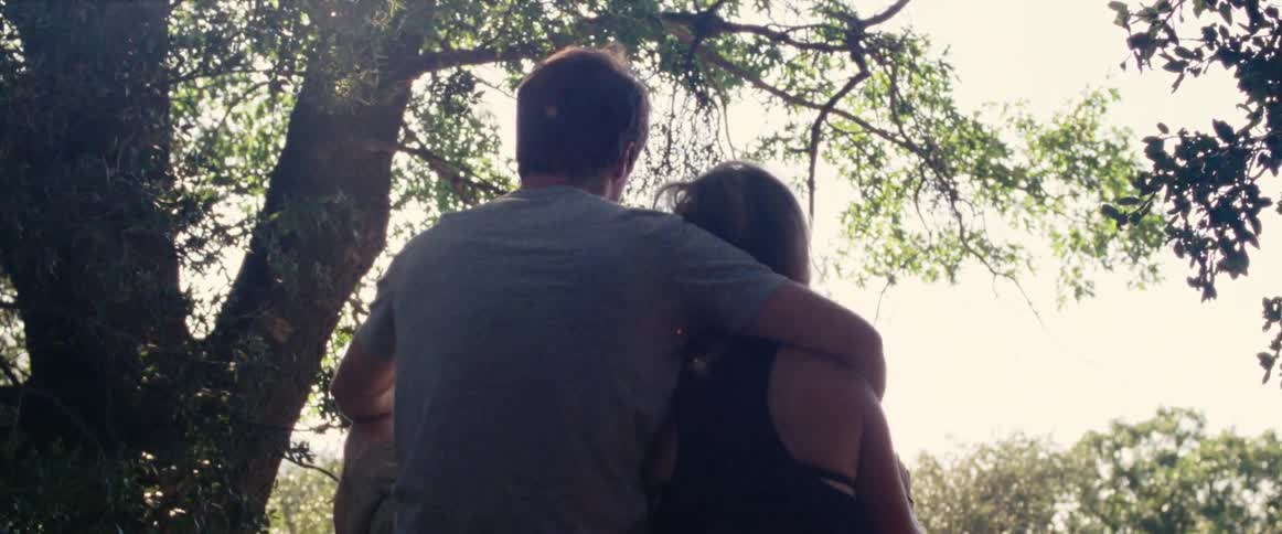 A man has his arm over a woman's shoulder as they take in a view