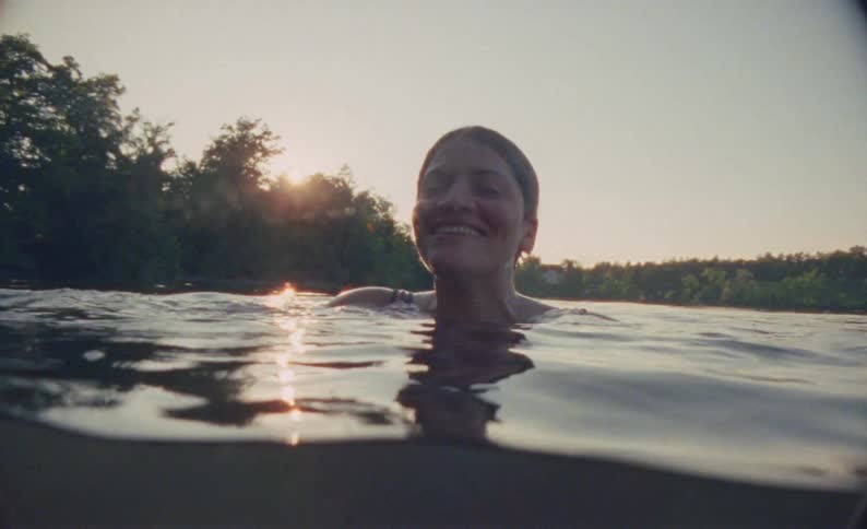 Woman with a happy expression in the late afternoon swimming in a lake