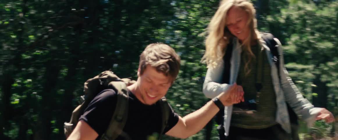 Man and woman walk down a hill in the woods