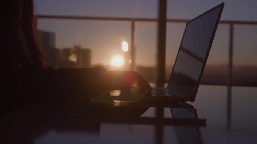 A person sits at a desk and types on a laptop keyboard
