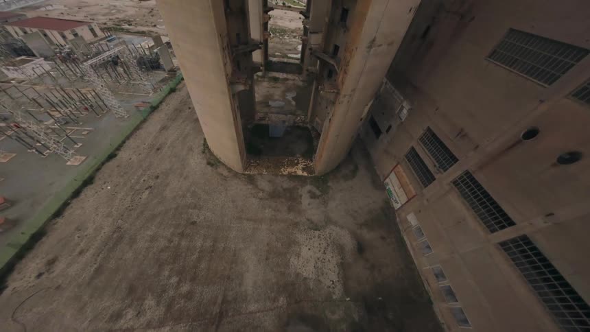 Ruined concrete towers frame the distant urban landscape and the coast