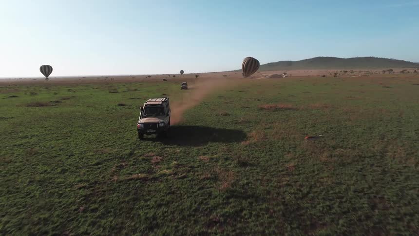 The vehicles drive away from the hot air balloons