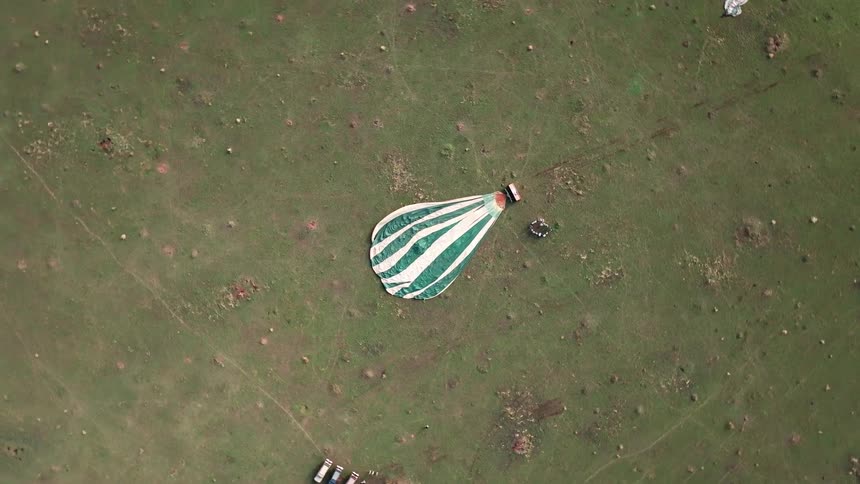 A hot air balloon with people around it prepares for take off from the ground