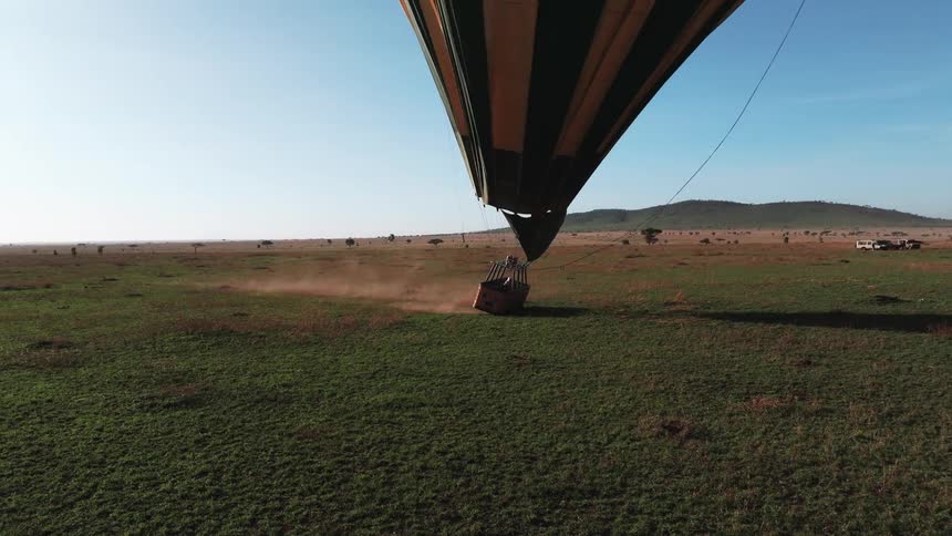 The hot air balloon drags across the grass