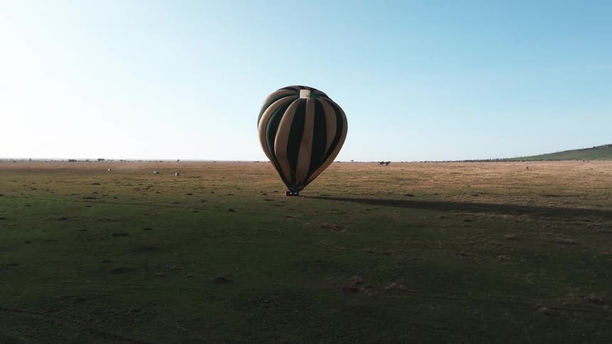 The hot air balloon tips over as it drags on the field