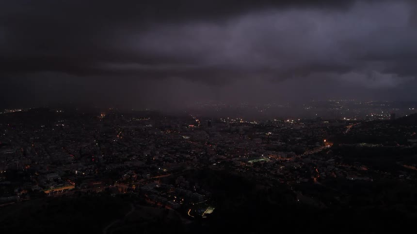 City lights glowing at dusk under dark clouds