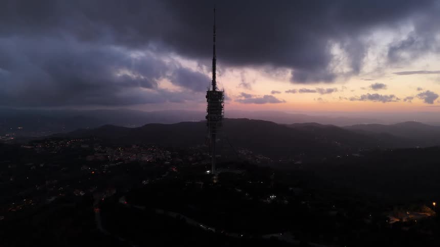 City tower at night with a dark cloudy sky overhead the last hues of sunset fading behind the clouds