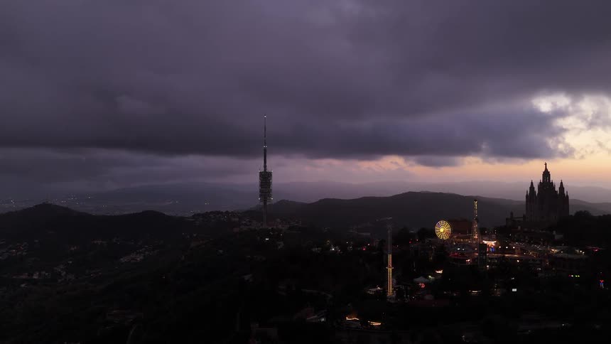 Amusement park lit up next to a church on the hill at dusk