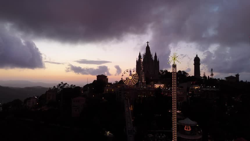 Church on the hill with a ferris wheel lit up at sunset