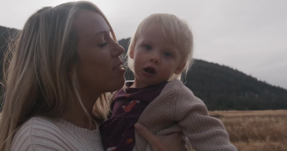 Woman holds a child in her arms in an open field