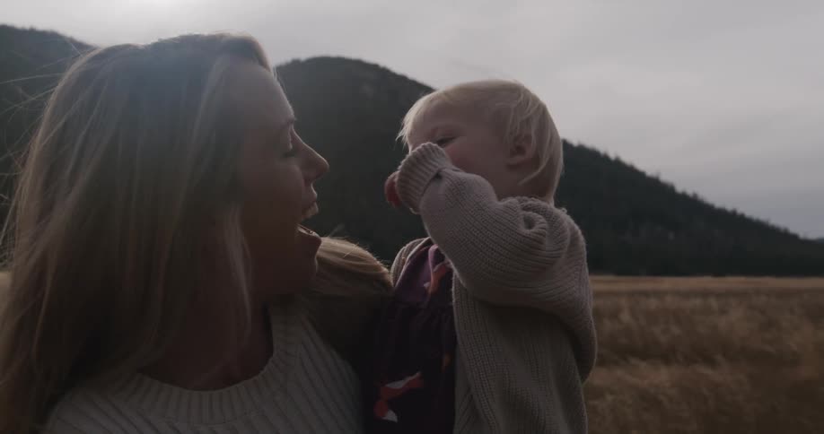 A parent holds a child and interacts with the child in a field