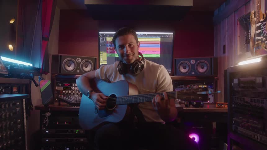 The man is playing the guitar in the studio