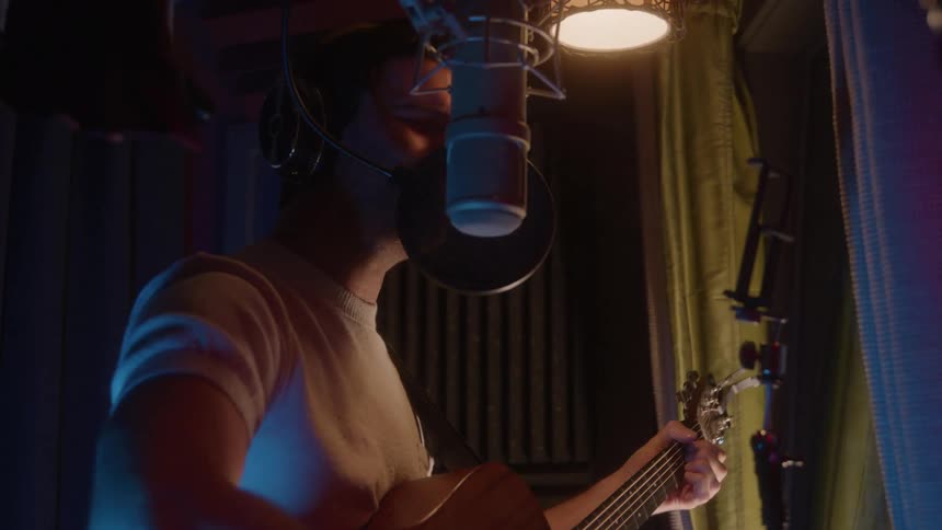 The man is singing into the microphone in the studio