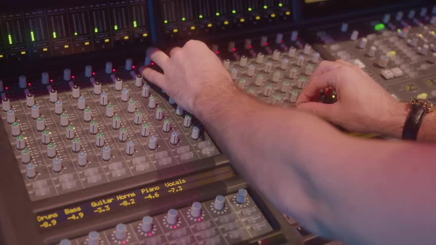 The man turns the knob on the sound mixer