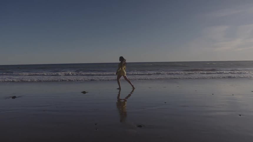 Woman walking and jumping by the sea