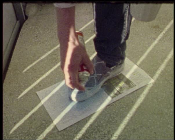 Person spraying sneakers placed on a newspaper