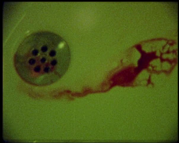 Red stain resembling blood flowing down the drain