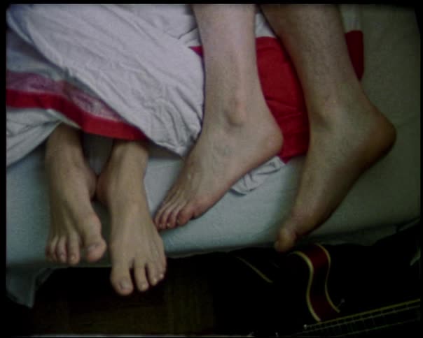 Feet of two people lying together in bed