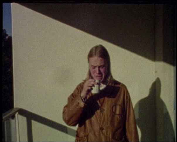The man drinks and winces from the taste