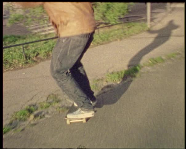 A man is skateboarding on a street passing by buildings and other people