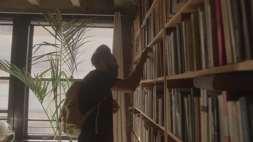 The man is browsing the books in the libary