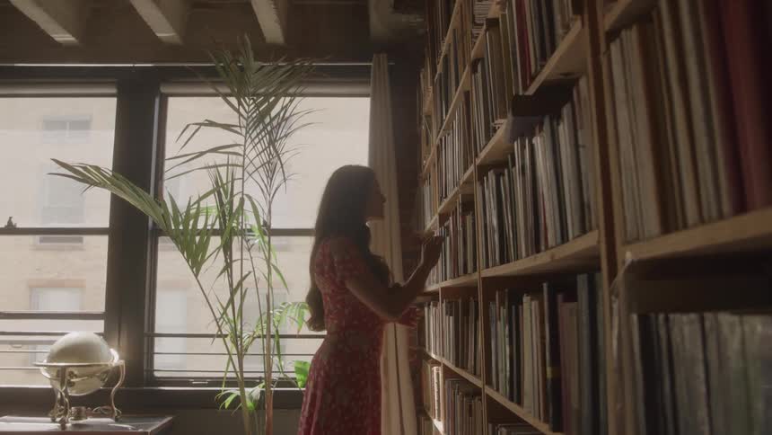 Woman picking a book from a library shelf