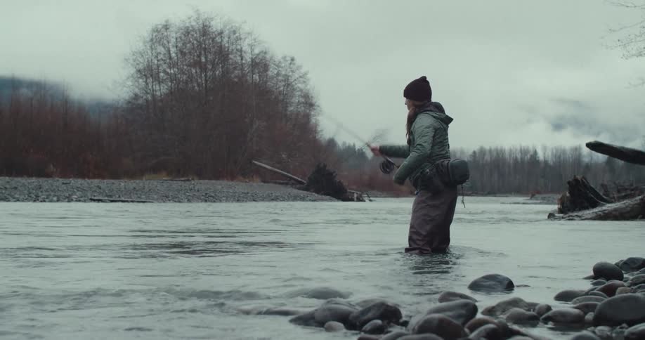 Woman fishing with a rod in a shallow river