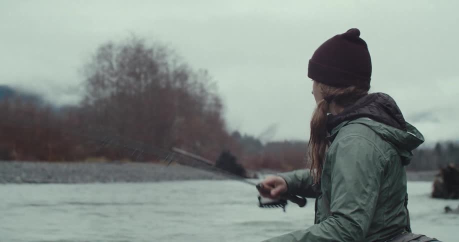 Woman fishing in a river with a fishing rod