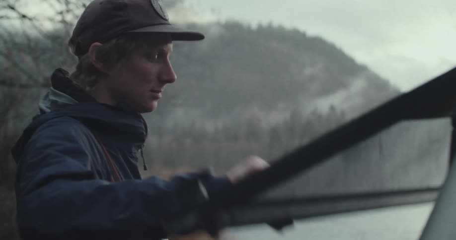 The man opens the back door of his vehicle by the river