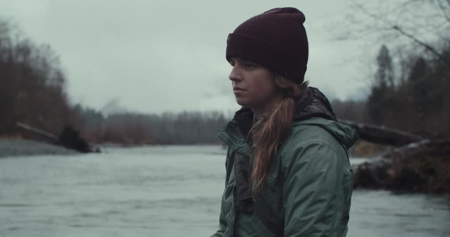 Woman wearing a beanie watching the river on a cloudy day