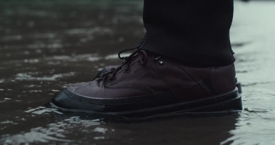 Dark brown shoe in a puddle of water during rain