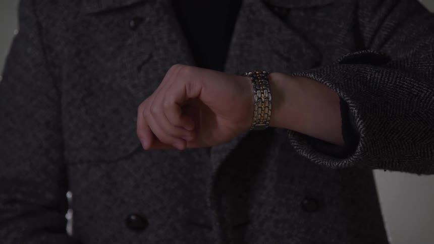 Person in a coat checking the time on a wristwatch