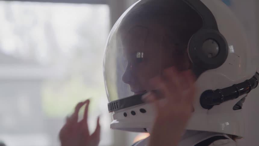 The girl puts on her space suit costume helmet