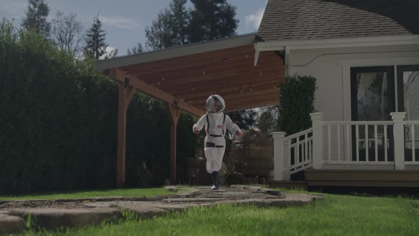 Little girl dressed as an astronaut running in the backyard