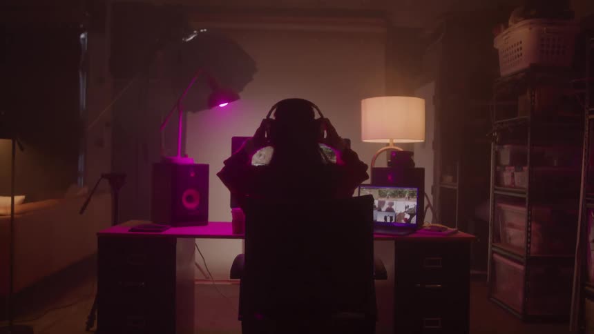 Woman sitting at a computer in her studio wearing a headset and looking intently at her screen
